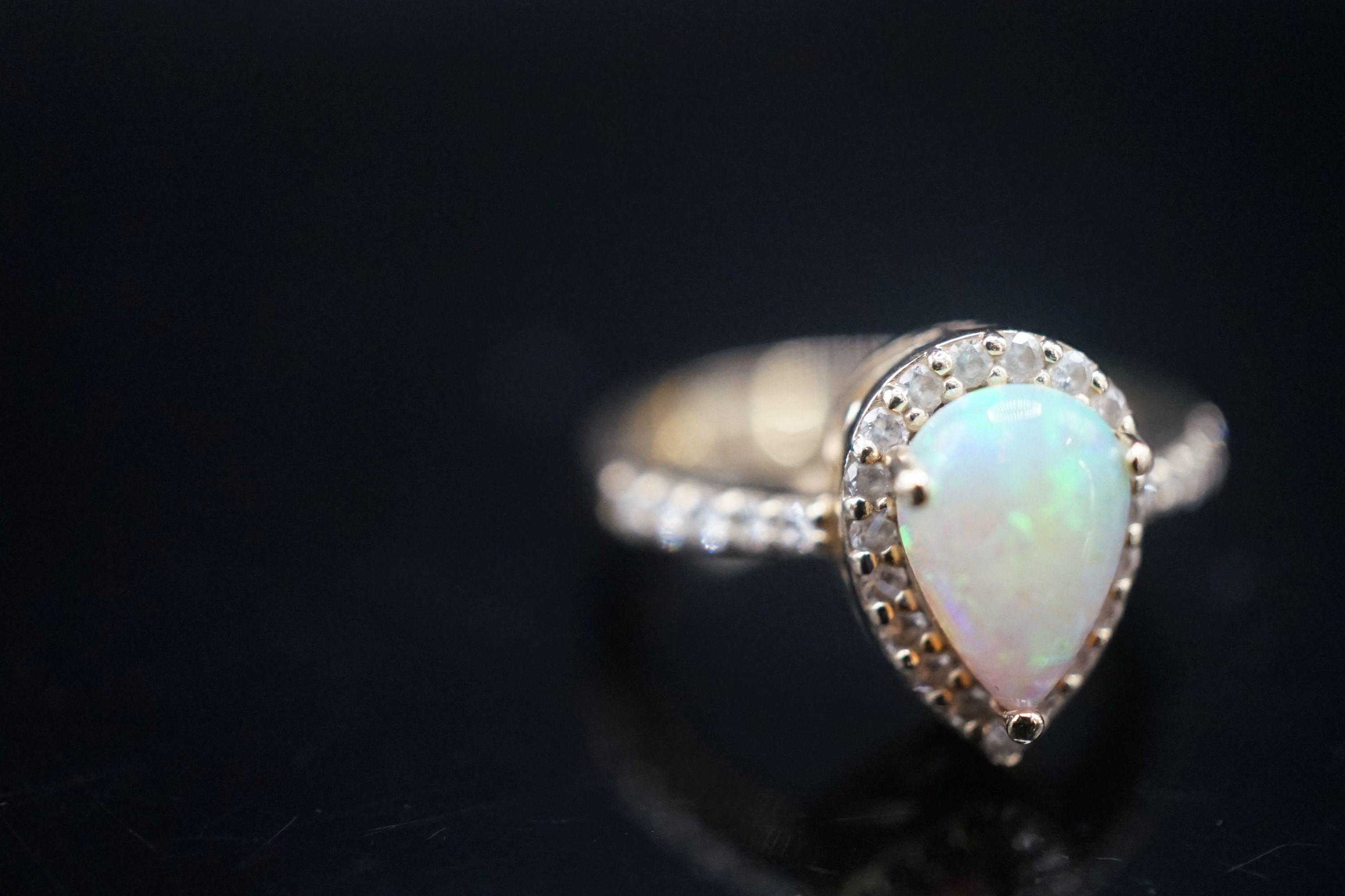 A modern 14k yellow meta, white opal and diamond set pear shape cluster ring, with diamond set shoulders, size K, gross weight 4.3 grams.